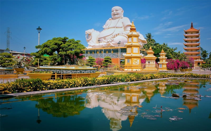 A large Buddha statue at Vinh Trang Pagoda, standing out in the lush garden.